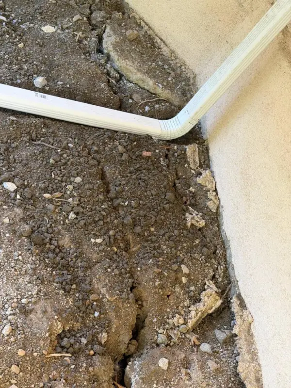 Plate 17: A downspout discharging at the wall base, with the soil below scoured into a trench.